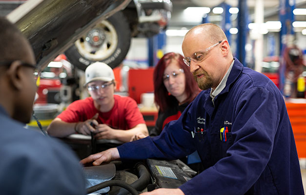 An Advisor and Two Students Working on a Car in the Lab.