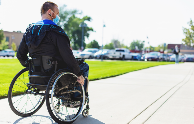 Individual using wheelchair on sidewalk